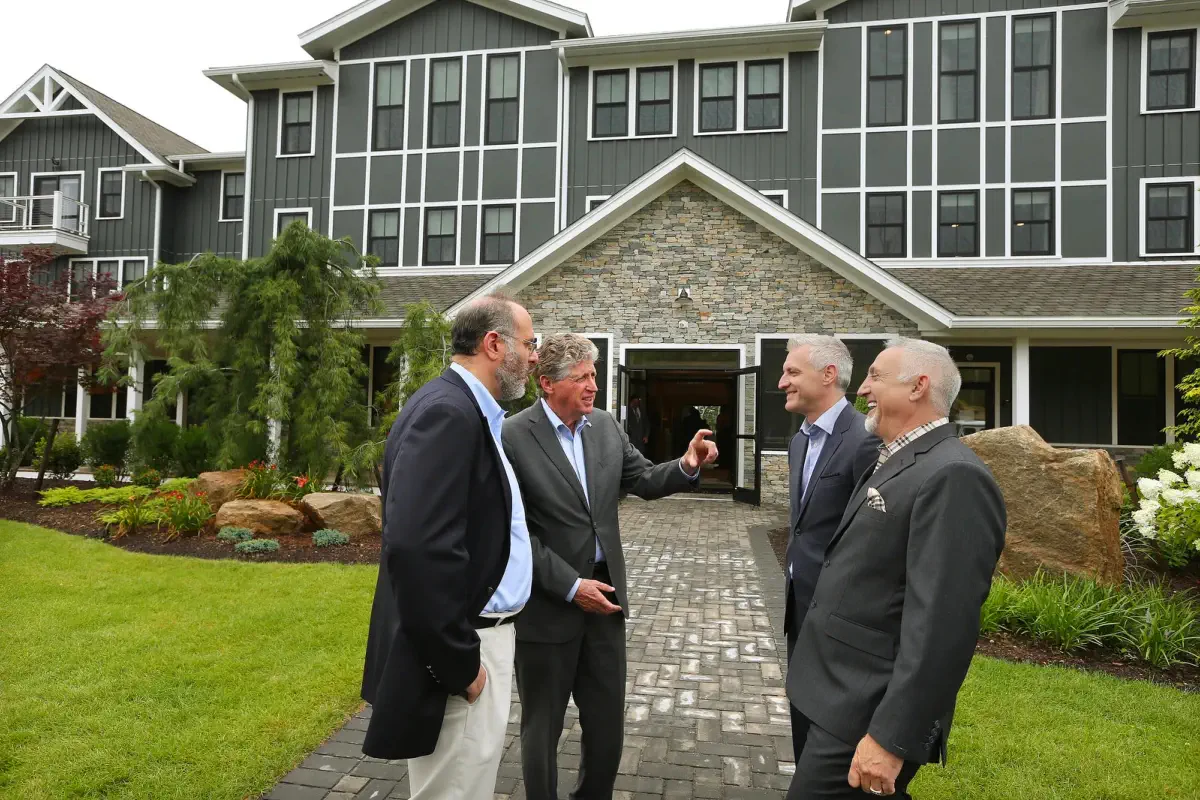 Gov. Dan McKee talks with Stefan Pryor, left, secretary of commerce; Dant Hirsch, second from right, president of the Ocean House Collection; and The Preserve's chairman, Paul Mihailides, right, at the entrance to the newly opened Hilltop Lodge, a spa and luxury hotel at The Preserve Sporting Club and Residences in Richmond.