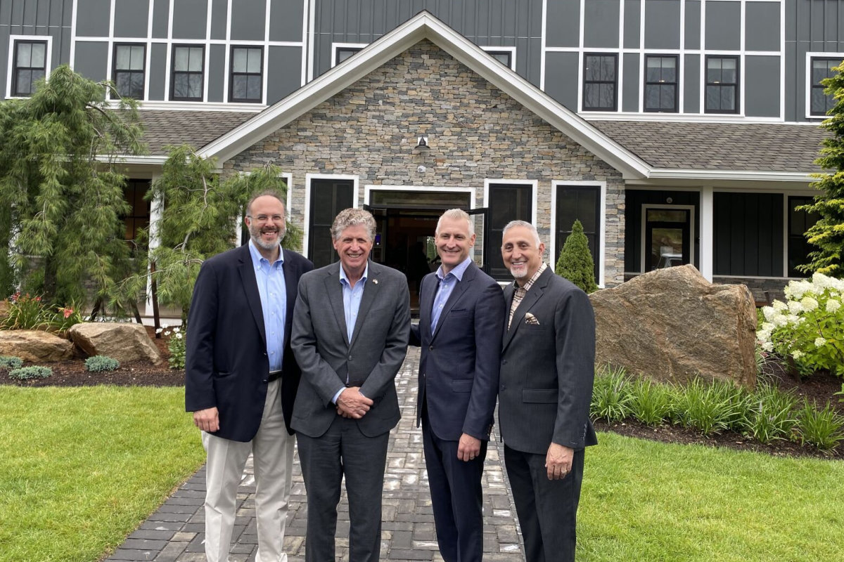 Gov. Dan McKee with officials at Hilltop Lodge's entrance.