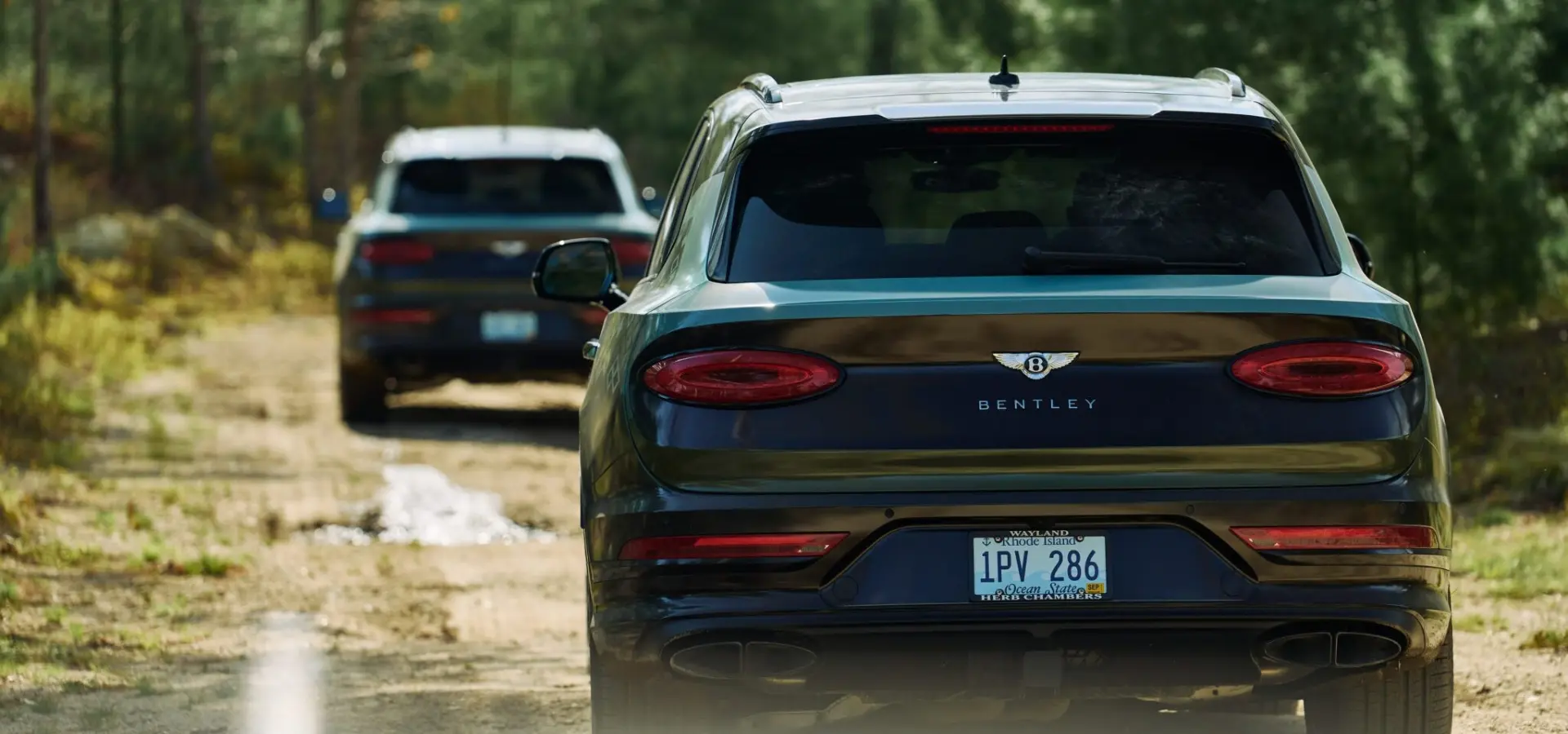 Two Bentley Bentayga SUVs driving through a forest trail at The Preserve Sporting Club